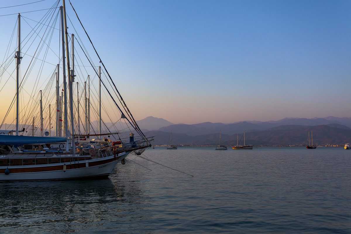 Gün batımında sakin bir koyda demirlemiş yelkenli tekneler
