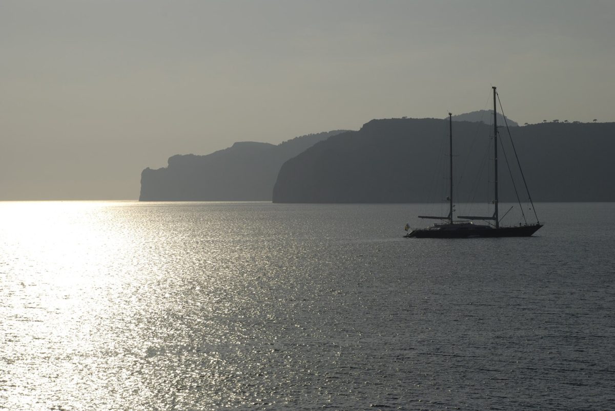 Segelyacht Silhouette auf dem Meer vor felsiger Küste