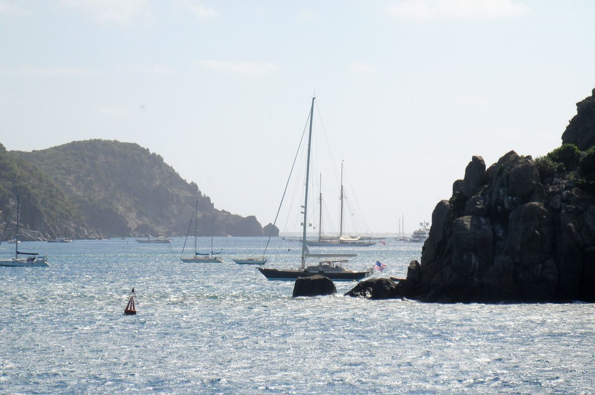 Sailboats anchored in a calm tropical bay near rocky cliffs